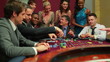 Men placing bets at roulette table watched by women
