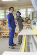 Carpenter and apprentice using industrial saw