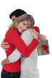 Woman holding gift hugging boyfriend