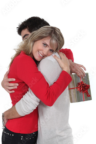 Photo: Woman holding gift hugging boyfriend Woman holding gift hugging boyfriend