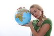 Woman in green resting her head against a large globe