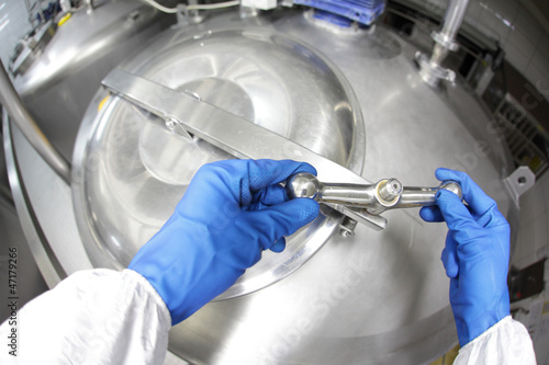 Photo: hands in blue Glover closing industrial process tank hands in blue Glover closing industrial process tank