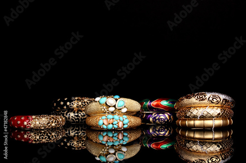 Photo: Beautiful golden bracelets isolated on black background Beautiful golden bracelets isolated on black background