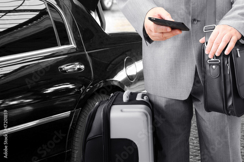 Photo: Traveling Businessman with His Luggage Using Phone Traveling Businessman with His Luggage Using Phone