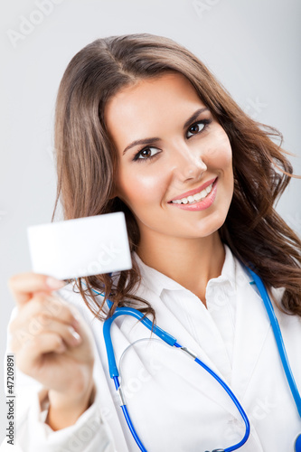 Photo: Young female doctor showing blank business card Young female doctor showing blank business card