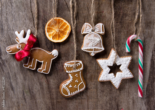Photo: Traditional gingerbread cookies hanging over wooden background Traditional gingerbread cookies hanging over wooden background
