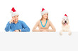 Photo: Smiling couple and dog with santa hats posing behind a panel Smiling couple and dog with santa hats posing behind a panel