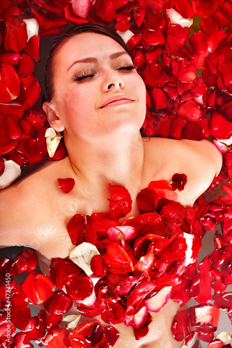 Photo: Beautiful young woman in rose petal swim water. Beautiful young woman in rose petal swim water.