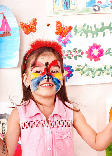 Photo: Child with face painting in play room. Child with face painting in play room.