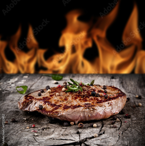  Delicious beef steak on wood with flames on backgrouns