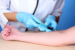 Nurse takes blood from the veins on blue background