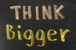 Think bigger concept, words on blackboard