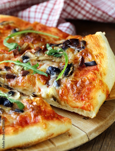 Photo: Italian pizza with mushrooms and olives on a wooden board Italian pizza with mushrooms and olives on a wooden board