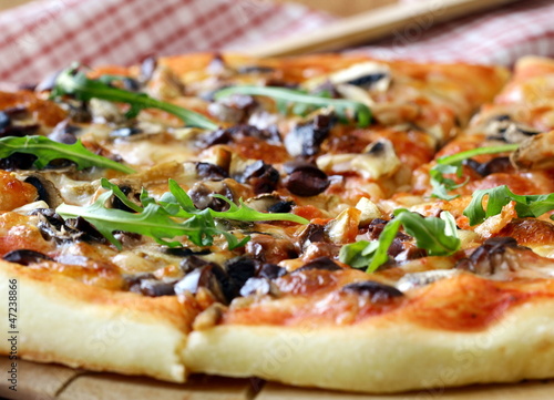 Photo: Italian pizza with mushrooms and olives on a wooden board Italian pizza with mushrooms and olives on a wooden board