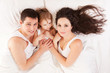 Foto: Happy family, mother, father and daughter resting on the white b Happy family, mother, father and daughter resting on the white b