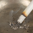 Burning cigarette in an old tin ashtray