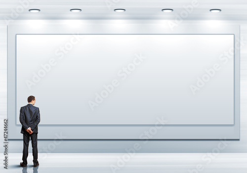 Photo: Business person standing near a blank billboard Business person standing near a blank billboard