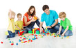 Photo: Happy family. Parents with three kids playing blocks over white Happy family. Parents with three kids playing blocks over white