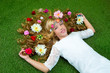 Blond spring girl with flowers on hair over grass