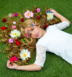 Blond spring girl with flowers on hair over grass