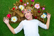 Blond spring girl with flowers on hair over grass