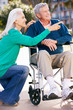 Senior Woman Pushing Husband In Wheelchair