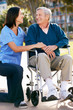 Carer Pushing Senior Man In Wheelchair
