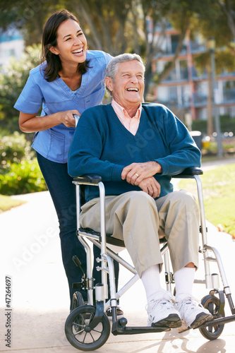 Photo: Carer Pushing Senior Man In Wheelchair Carer Pushing Senior Man In Wheelchair