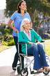 Carer Pushing Senior Woman In Wheelchair