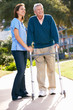 Carer Helping Senior Man With Walking Frame
