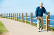 Senior Man Walking Along Path By The Sea