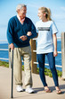 Teenage Volunteer Helping Senior Man Walking Along Path By The S