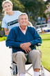Teenage Volunteer Pushing Senior Man In Wheelchair