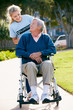 Teenage Volunteer Pushing Senior Man In Wheelchair