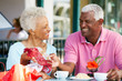 Senior Couple Enjoying Snack At Outdoor Café After Shopping