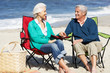 Senior Couple Sitting On Beach In Deckchairs Having Picnic