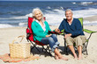 Senior Couple Sitting On Beach In Deckchairs Having Picnic