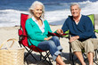 Senior Couple Sitting On Beach In Deckchairs Having Picnic