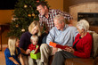 Multi Generation Family Opening Christmas Presents In Front Of T