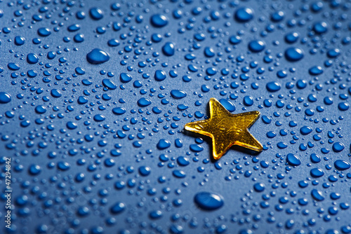 Photo: a little golden star and blue water dorops - christmas concept a little golden star and blue water dorops - christmas concept