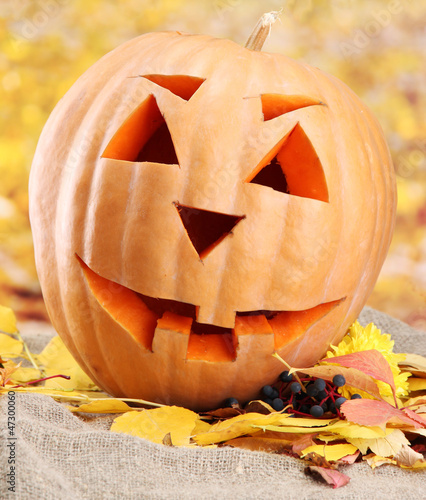 Photo: halloween pumpkin and autumn leaves, on yellow background halloween pumpkin and autumn leaves, on yellow background