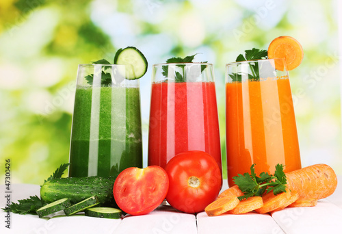 Photo: Fresh vegetable juices on wooden table, on green background Fresh vegetable juices on wooden table, on green background