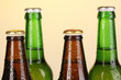 Coloured glass beer bottles on yellow background