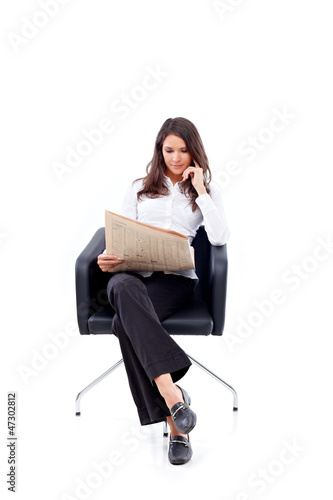 Photo: Casual 20s woman reading stock rates in newspaper Casual 20s woman reading stock rates in newspaper