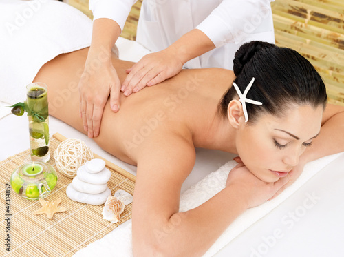 Photo: Woman on therapy massage of back in spa salon Woman on therapy massage of back in spa salon