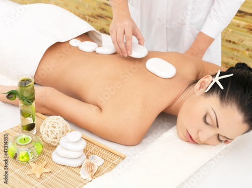 Photo: Woman having hot stone massage of back in spa salon Woman having hot stone massage of back in spa salon