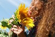 portrait woman sniffs sunflower