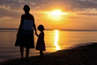 Mother and kid silhouettes on sunset beach, family vacation