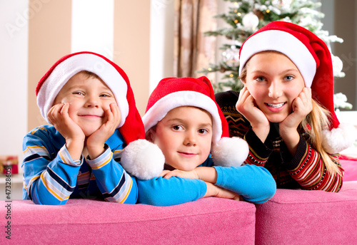 Photo: Christmas Children. Happy Little Kids wearing Santa's Hat Christmas Children. Happy Little Kids wearing Santa's Hat