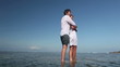 Happy man embracing his girlfriend and standing in ocean